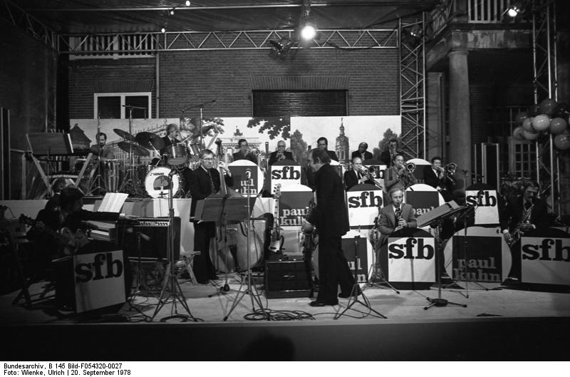 Paul Kuhn 1978 als Bandleader der SFB-Bigband in Bonn beim "Laubenpieperfest" in der Landesvertretung Berlin; Quelle: Deutsches Bundesarchiv, Digitale Bilddatenbank, B 145 Bild-F054320-0027; Fotograf: Ulrich Wienke / Datierung: 20.09.1978 / Lizenz CC-BY-SA 3.0.; Originalfoto und Beschreibung: Deutsches Bundesarchiv B 145 Bild-F054320-0027 bzw. Wikimedia Commons