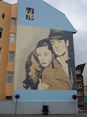 Wandmalerei beim früheren Standort des "Kommunalkino Bremen" (als "Kino 46") an der Waller Heerstraße. Zu sehen sind Veronica Lake und Alan Ladd in einem Standbild aus "Die Narbenhand". Urheber: City 46/Kommunalkino Bremen e.V.; Lizenz: CC BY-SA 3.0 DE; Quelle: "City 46" bzw. Wikimedia Commons