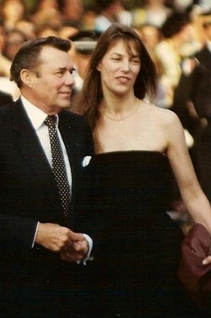 Dirk Bogarde mit Jane Birkin 1990 anlässlich des Filmfestivals in Cannes; Quelle: Wikipedia (englisch) bzw. Wikimedia Commons; Ausschnitt eines Originalfotos von  Georges Biard (Urheber); Lizenz CC-BY-SA 3.0.