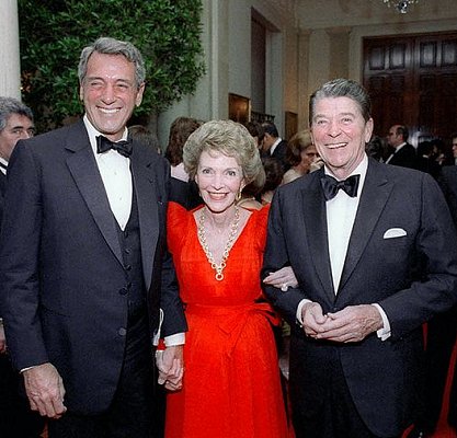 Rock Hudson (l.) mit US-Präsident Ronald Reagan und dessen Gattin Nancy am 15. Mai 1984 anlässlich eines Dinners im "Weißen Haus"; Lizenz: Gemeinfreiheit; Quelle: Wikimedia Commons