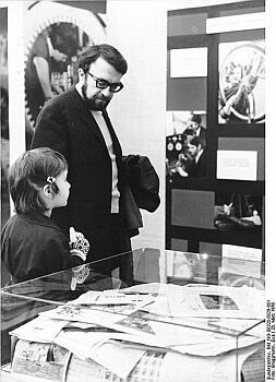 Foto: Wolfgang Kieling 1968;  Historische Originalbeschreibung: 30.2.1968 Berlin, Vietnam-Ausstellung: Der Schauspieler Wolfgang Kieling, besuchte mit seiner Tochter Anett am�20.3.1968 die Vietnam-Ausstellung in der Berliner Friedrichstrasse. Er informierte sich über die Solidaritätsbeweise der Bevölkerung der�DDR für das heldenhaft kämpfende vietnamesische Volk. Quelle: Deutsches Bundesarchiv, Digitale Bilddatenbank, Bild 183-G0320-0029-001; Fotograf: Eva Brüggmann / Datierung: 20. 3.1968 / Lizenz CC-BY-SA 3.0.