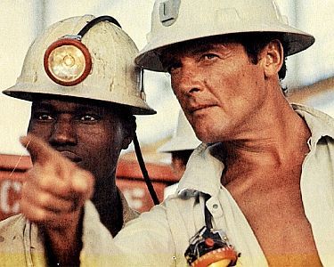 "Gold": Szenenfoto mit Roger Moore (r.) als der Untertage-Betriebsleiter Rod Slater: mit freundlicher Genehmigung von "Pidax Film", welche das Abenteuer am 17. Oktober 2024 auf DVD herausbrachte.