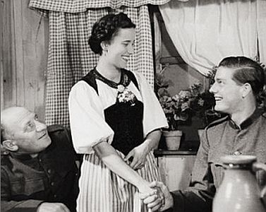 Szenenfoto mit Lisa Della Casa als Vreneli und Paul Hubschmid als Reinhold Wipf sowie Heinrich Greteler (links) als dessen v�terlicher Freund Soldat Leu; Quelle: �cyranos.ch mit weiteren Infos zum Film; Foto mit freundlicher Genehmigung von Peter Gassmann (Praesens-Film AG, Z�ich); Copyright Praesens-Film AG