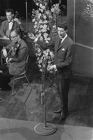 Rudi Carrell am 9.Februar 1960 beim Vorentscheid zum "Eurovision Song Contest" in Hilversum; Rechteinhaber: Nationaal Archief (Den Haag, Rijksfotoarchief; Bestandsnummer: 911-0172); Urheber/Fotograf: Harry Pot / Anefo; Quelle: Wikimedia Commons; Lizenz: www.gahetna.nl/over-ons/open-data / CC BY-SA 3.0 NL